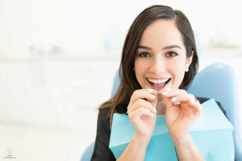 a woman in blue bip wearing invisalign clear aligners after considering between aligners vs braces in richmond, tx