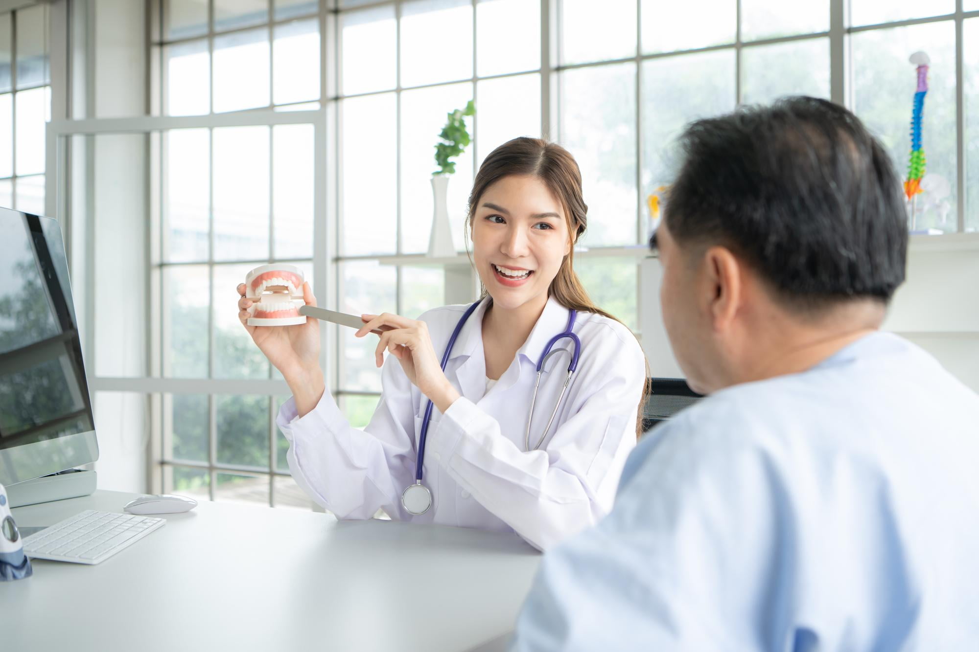 In a bright office at Elara Orthodontics in Richmond or Houston, TX, a female doctor explains FME benefits to a male patient.
