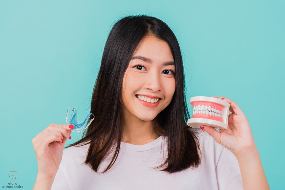 portrait young asian beautiful woman smiling holding silicone orthodontic retainers - Retainer vs Braces in Houston and Richmond, TX
